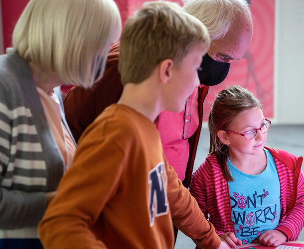 Interactive science exhibition photo showing two children and their grandparents interacting with an exhibit