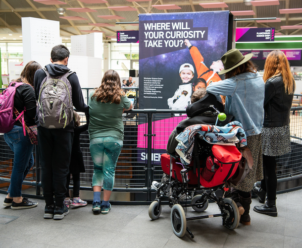 Accessibility photo showing a group of people watching a science demonstration from a balcony