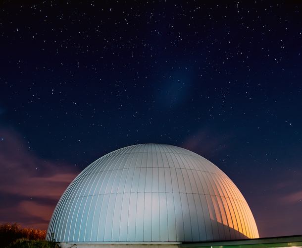 A photo of the outside of the Planetarium against a starry night sky