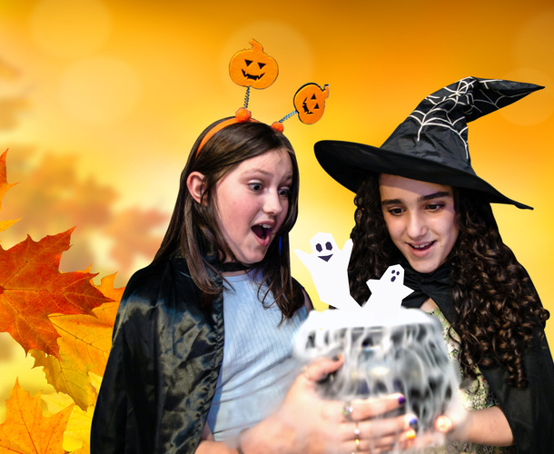 Two girls in Halloween costumes looking at a cauldron