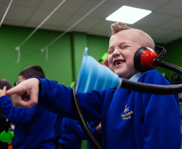 A boy laughs while wearing a science headset
