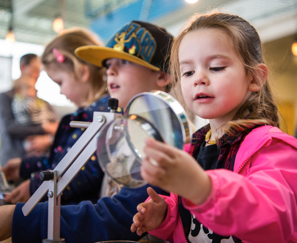 A young girl studies a scientific sample through a magnifying glass