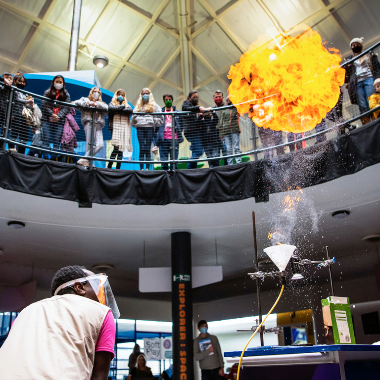 A live fire experiment at Winchester Science centre watched by lots of people on a balcony