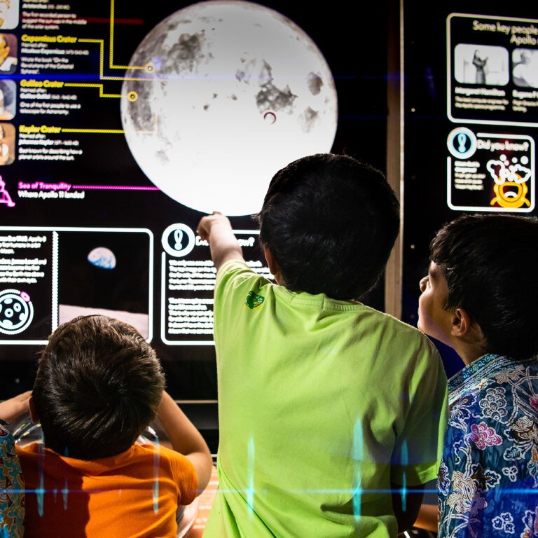 A group of boys point at an image of the moon