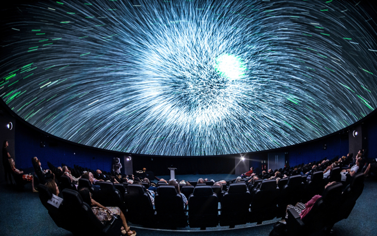 Planetarium photo showing the audience looking up at a starry sky on the screen