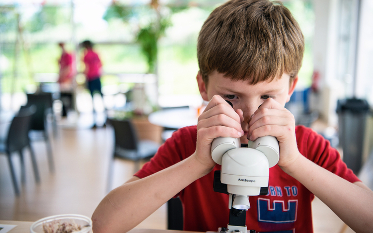 Bio:Space nature zone photo showing a boy looking down a microscope