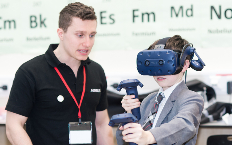 A school student uses a virtual reality headset while being instructed by a professional