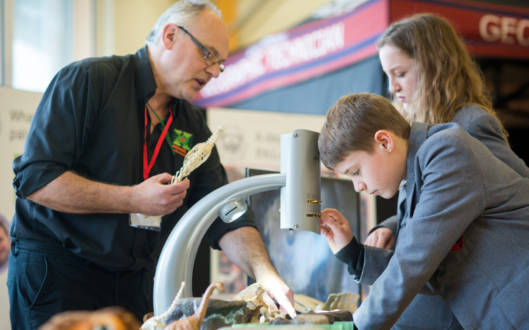 An exhibitor shows students fossils at a science festival