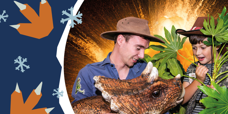 Christmas promotional photo showing a young boy looking excitedly at a dinosaur being held by a dino ranger