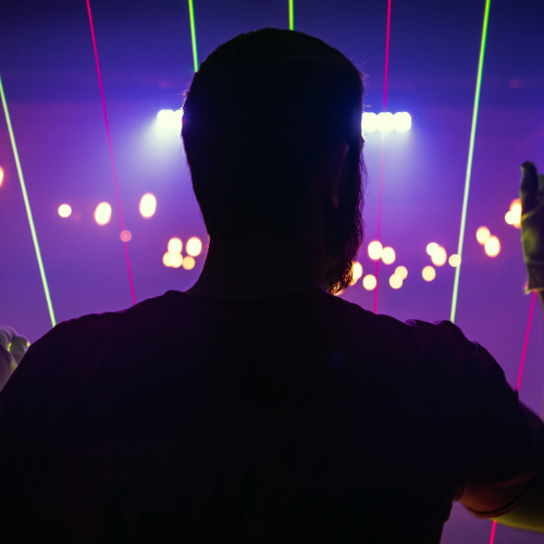 A silhouette of a person in front of laser beam lights