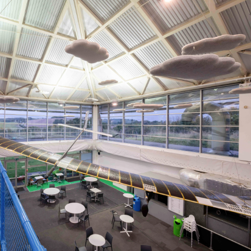 The Zephyr 6 aircraft suspended from the ceiling of the Science Centre, flying above the café tables