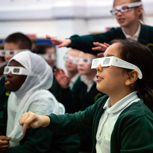 School children wearing 3D glasses and pointing in front of them