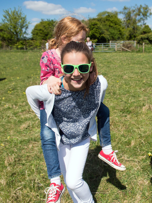 A young girl enjoying a piggy back from her older sister while outside