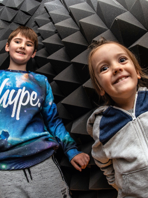 Interactive science exhibition photo showing a boy and a girl inside the scream chamber, looking excited