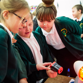 Three school children looking at a heat sensor as part of a workshop activity
