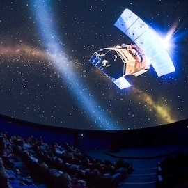 Planetarium photo showing the audience in the auditorium looking at the screen which is displaying a starry night sky