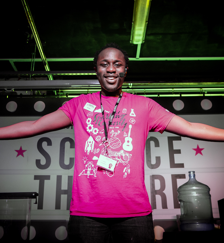Live science show photo showing a male presenter smiling to the audience with his arms open