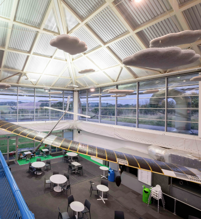 The Zephyr 6 aircraft suspended from the ceiling of the Science Centre, flying above the café tables