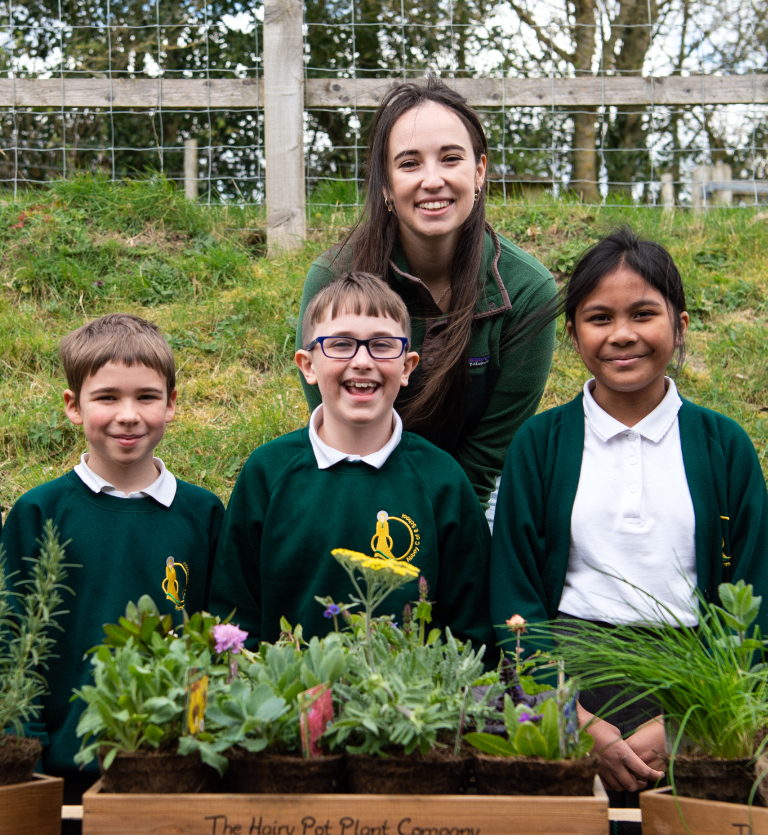 TV presenter Megan McCubbin poses with some school children in front of some plants outside