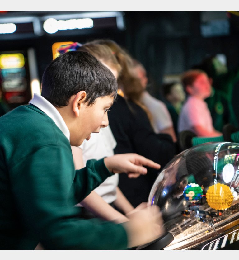 Interactive science exhibition photo showing a boy in school uniform pointing and looking with wonder at an exhibit