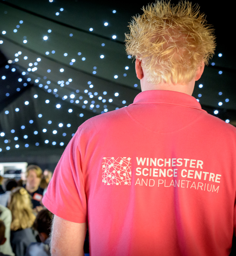 Man in a Winchester Science Centre polo shirt with his back to the camera