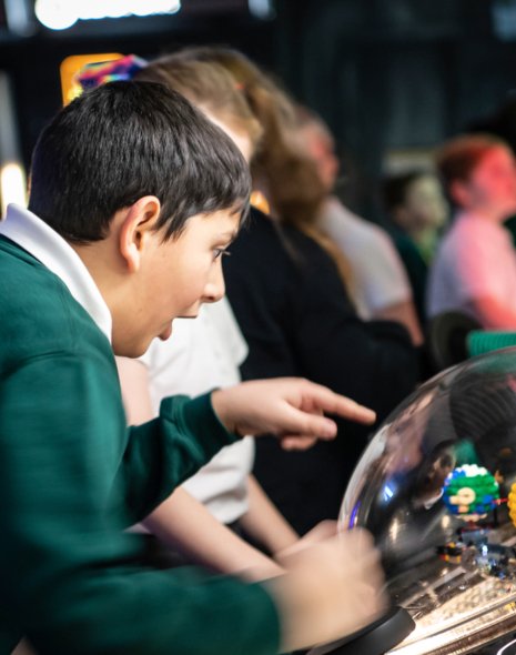 Interactive science exhibition photo showing a boy in school uniform pointing and looking with wonder at an exhibit