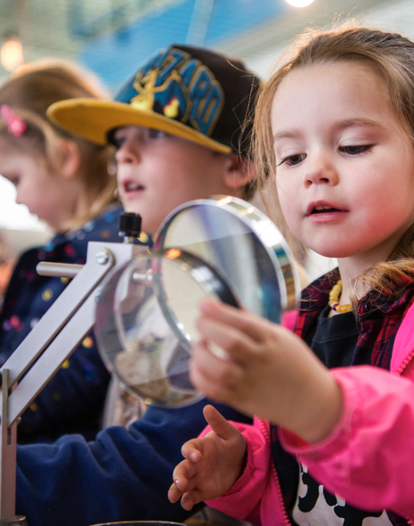 A young girl studies a scientific sample through a magnifying glass