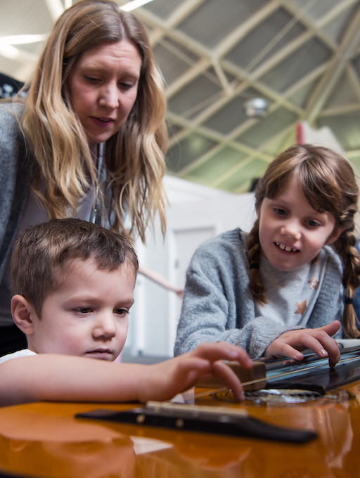 Interactive science exhibition photo showing a family engaging with an exhibit, with one of the children in a wheelchair