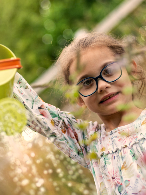 A little girl holds a butterfly net sitting in a field